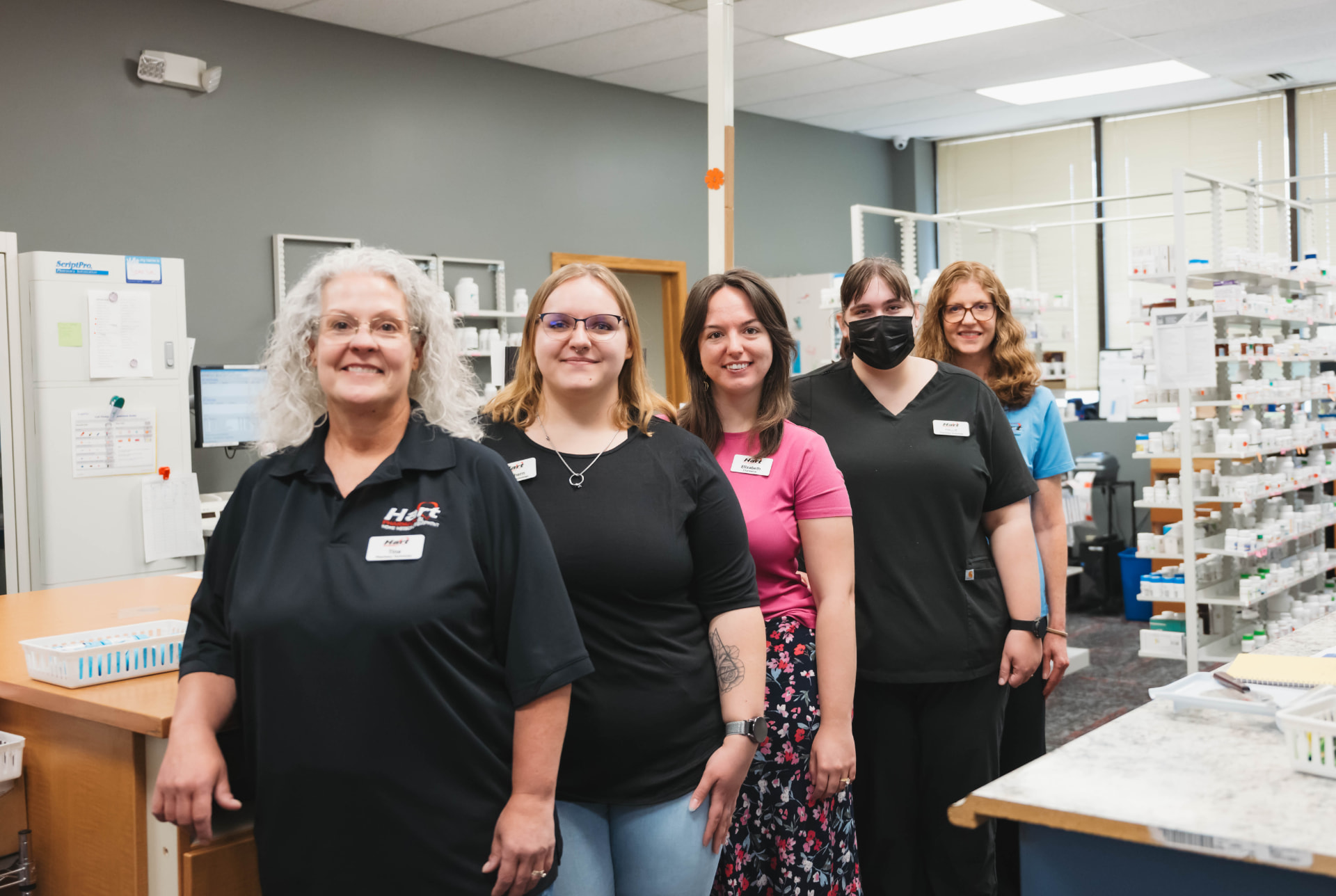 The Hart Pharmacy at Comcare team standing together behind the pharmacy counter